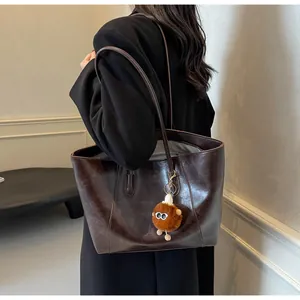 Vue latérale du grand sac cabas marron vintage avec pendentif monstre en peluche doux