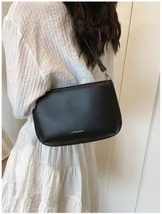 Mannequin portant un sac bandoulière en cuir noir mat au design rectangulaire minimaliste