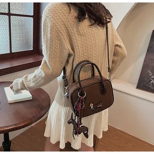 Brown crossbody bag featuring dachshund embroidery and charm, shown on model back