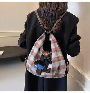 Detailansicht des karierten Rucksacks mit schwarzer Katze und blauer Fischbestickung