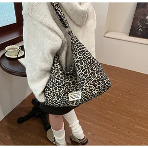Large leopard print canvas crossbody bag worn by a model in a cozy indoor setting