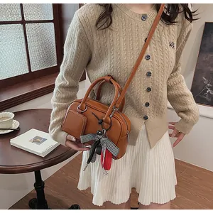 Brown leather handbag detail featuring adjustable strap and elegant decorative scarf detail