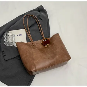 Détail du cabas vintage en cuir caramel avec pendentif monstre en peluche sur tissu