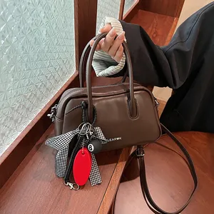 Brown leather bowling bag with vintage handles and creative hanging charms