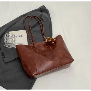 Gros plan détaillé du cabas en cuir PU marron avec texture fine et pendentif d'ours