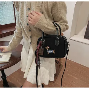 Detail of black handbag with puppy embroidery, chocolate charm and plaid scarf accent