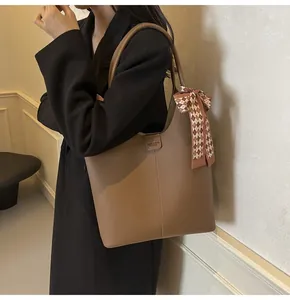 Close-up of brown lychee-grain tote bag featuring a decorative checkered scarf on the handle