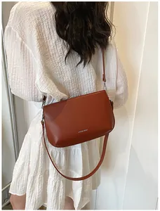 Vue de dos d'un mannequin portant un sac bandoulière marron avec une robe blanche plissée
