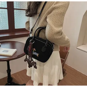 Detail of black leather handbag featuring dachshund embroidery and woven rope charm accessories
