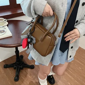 Vintage brown bowling handbag with a retro bow charm and adjustable crossbody shoulder strap