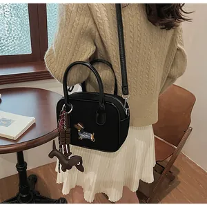 Detail of black handbag featuring embroidered dachshund patch and cute puppy charms
