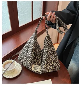 Detailed close-up of a large leopard print canvas hobo bag on a rustic wooden table