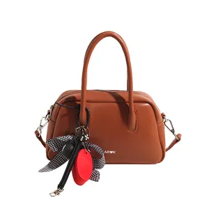 Detail of caramel leather bowling bag featuring decorative bow and logo branding