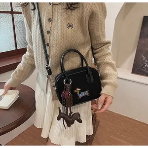 Detail of black handbag featuring dachshund embroidery and matching brown puppy charm