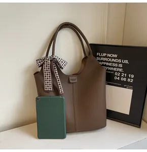 Detail of dark brown lychee leather tote bag with stylish checkered silk ribbon handle decoration
