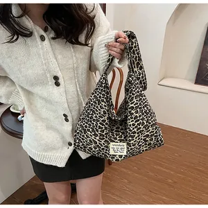 Detail of leopard print canvas shoulder bag with branded white woven label and texture