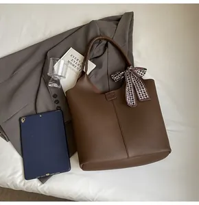 Detail of brown litchi textured tote bag with checkered silk scarf and office accessories