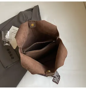 Interior detail of brown suede tote bag with zipper pouch and checkered scarf accessory