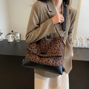 Leopard print crossbody bag with black leather base and wide strap in lifestyle scene
