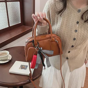 Brown Boston bag with dual handles and checkered ribbon, styled with beige knitwear