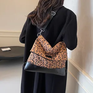 Chic leopard print canvas shoulder bag with black leather base shown on a model