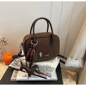Detail of dark brown handbag featuring dachshund embroidery and matching leather charm