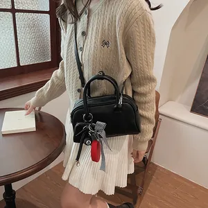Minimalist black leather crossbody bag for women with decorative ball and ribbon charms