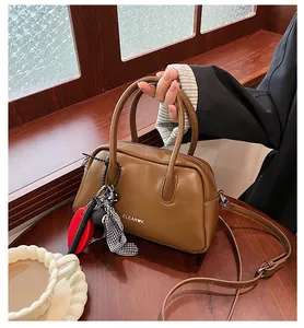 Detail of a brown leather bowling bag with vintage checkered bow and crossbody strap