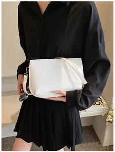 Détail d'un sac bandoulière blanc minimaliste avec fine lanière et logo sur un mannequin