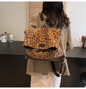 Detail view of leopard print shoulder bag with black leather base worn in a cafe setting