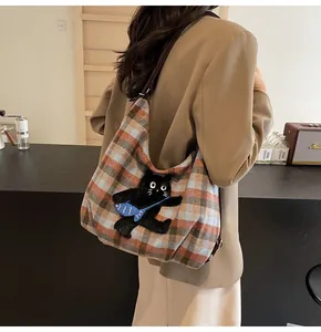 Detailansicht der Woll-Karostruktur und Katzenstickerei auf einer großen Shopper-Tasche