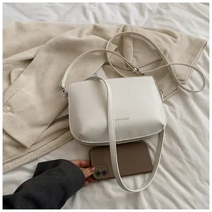 Vue détaillée d'un sac bandoulière en similicuir blanc avec logo embossé et fine sangle