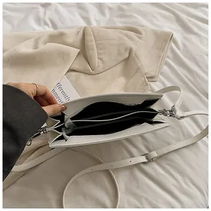 Vue de dessus d'un sac à bandoulière blanc crème montrant trois compartiments de rangement