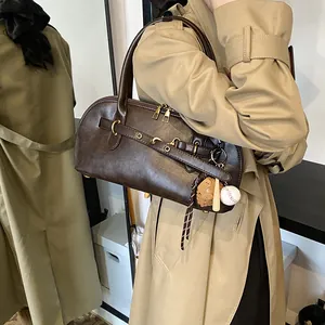 Retro dark brown shell bag with baseball charms and gold hardware on a beige coat model