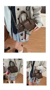 Detailed close-up of dark brown leather bowling bag with stylish charms and shoulder strap