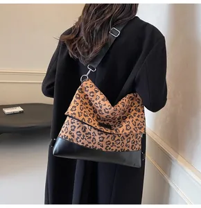 Detail of leopard print tote bag with black leather bottom and adjustable strap
