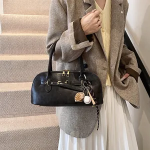 Retro black leather shoulder bag with gold hardware and baseball charm on model