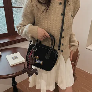 Chic black handbag with puppy embroidery and playful charms on a stylish knit cardigan model