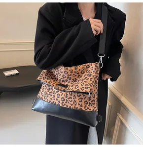 Detail view of the leopard print crossbody bag with silver buckle and black canvas strap