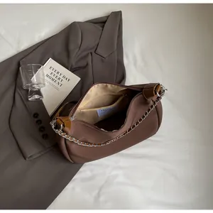 Détail du sac à dos marron montrant la chaîne en métal argenté et l'étiquette intérieure