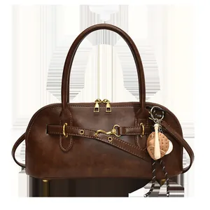 Close-up of brown leather shell bag with oil wax texture and baseball charm detail