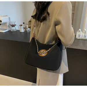 Détail d'un sac à bandoulière en nylon noir avec chaîne argentée et cuir marron
