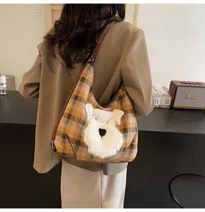 Detailansicht der karierten Tweed-Tasche mit Hunde-Aufnäher an der Schulter des Models