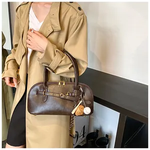 Detail of dark brown vintage shell bag with dual gold zippers and baseball charm