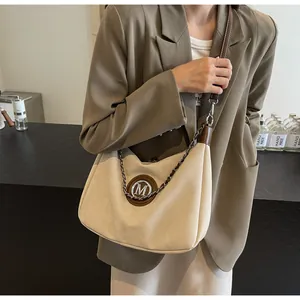 Détail du sac rétro en texture ivoire mate avec logo M rond et décoration de chaîne