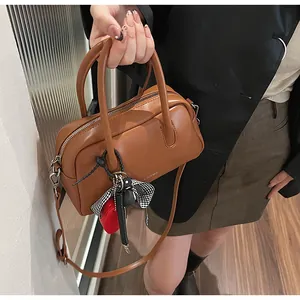 Top view of brown bowling handbag with decorative heart charm and patterned bow detail
