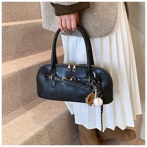 Close-up of black retro shell bag with gold hardware and creative baseball charm detail