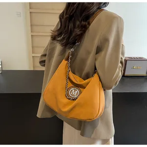 Détail du sac hobo en daim jaune avec logo M doré et bordure en chaîne gourmette