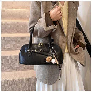 Detail of black shell handbag with baseball charms and metallic hardware on steps