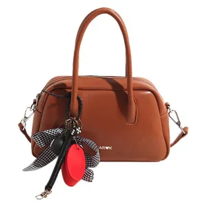 Brown leather bowling bag with stylish charms and top handles for modern women